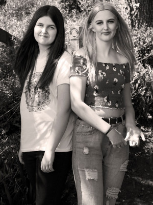 An image of two sisters standing back to back.