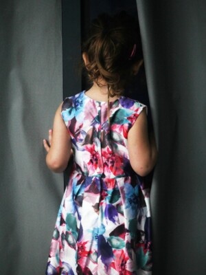 A well shot photo of a girl peaking between two curtains.