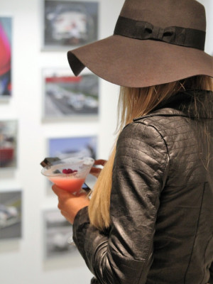 A well shot photo of a woman with a stylish hat drinking a cocktail.