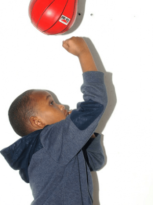 A well shot photo of a boy punching a speed bag.