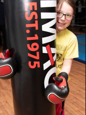 An image of a little girl hugging a punching bag.