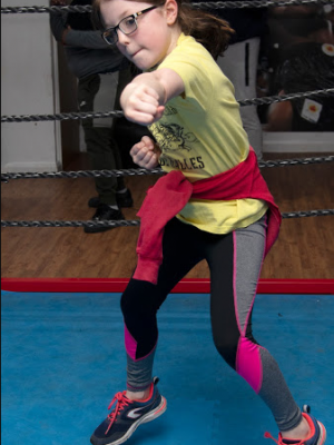 A well shot photo of a little girl shadow boxing in a boxing ring