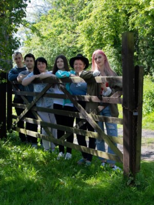 A well shot photo of a family standing together at a fence.