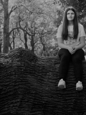 A well shot photo of a girl sitting on a log.