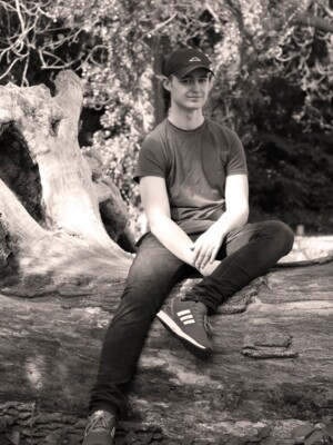 A well shot photo of a man sitting on a log.
