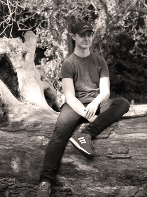 A well shot photo of a man sitting on a log.