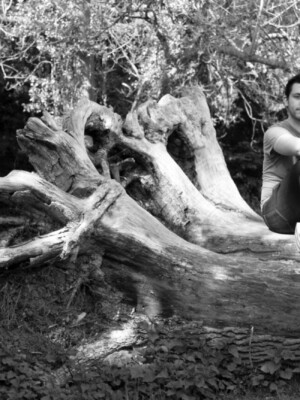 A well shot photo of a man sitting on a log.