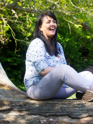 A well shot photo of a woman sitting on a log.