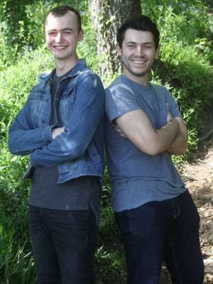 A well shot photo of a two men standing back to back.